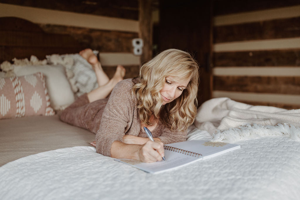 woman lying on bed journaling