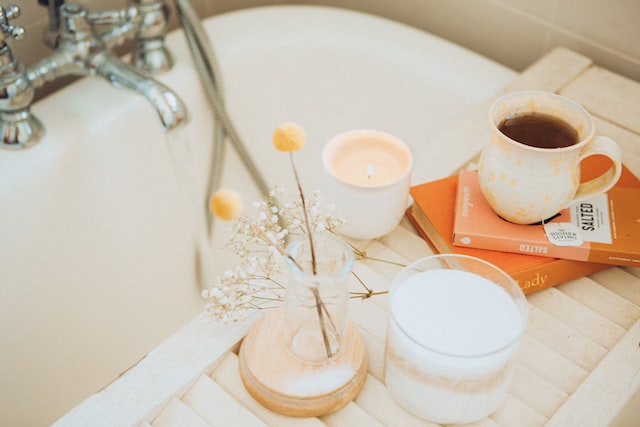 Bath drawn up as an act of self-love with flowers, a drink and candle